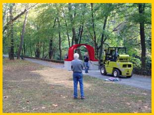 Someone watches workers, including one in a small, yellow construction vehicle. by the Red Arch on the Karl Stirner Arts Trail in Easton, Pennsylvania.