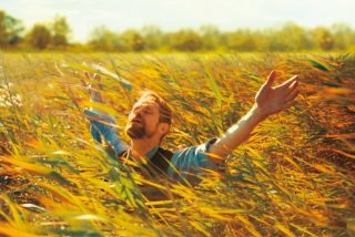 Willem Dafoe stands in a field during a scene in the film At Eternity's Gate, which focuses on artist Vincent van Gogh.