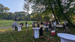 Guests talk by a table with food and win during a reception honoring artist Chakaia Booker on the Karl Stirner Arts Trail on Easton, Pennsylvania.