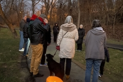 The backs of a group of people walking outside during the Winter Solstice event at the Karl Stirner Arts Trail