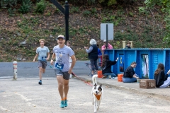 A man holding his dog on a leash runs by the blue McAteer Memorial Bridge at the Artful Dash 5K Run/Walk on the Karl Stirner Arts Trail in Easton, Pennsylvania.