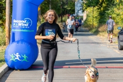 A woman holding a leash for her dog runs by the finish line at the Artful Dash 5K Run/Walk on the Karl Stirner Arts Trail in Easton, Pennsylvania.