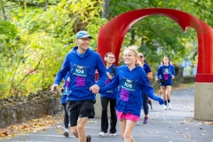 A man holds hands with a girl while both run near the iconic red arch sculpture at the Artful Dash 5K Run/Walk on the Karl Stirner Arts Trail in Easton, Pennsylvania.