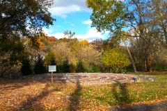 The Labyrinth circular path of rocks stands before trees with autumn leaves on the Karl Stirner Arts Trail in Easton, Pennsylvania.