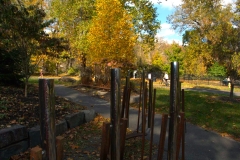 The Musical Chimes installation on a fall day with trees behind it and a bicycle rider traveling on the path of the Karl Stirner Arts Trail in Easton, Pennsylvania