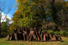 The brown metal sculpture Sprouts by Steve Tobin stands before autumn trees on the Karl Stirner Arts Trail in Easton, Pennsylvania.