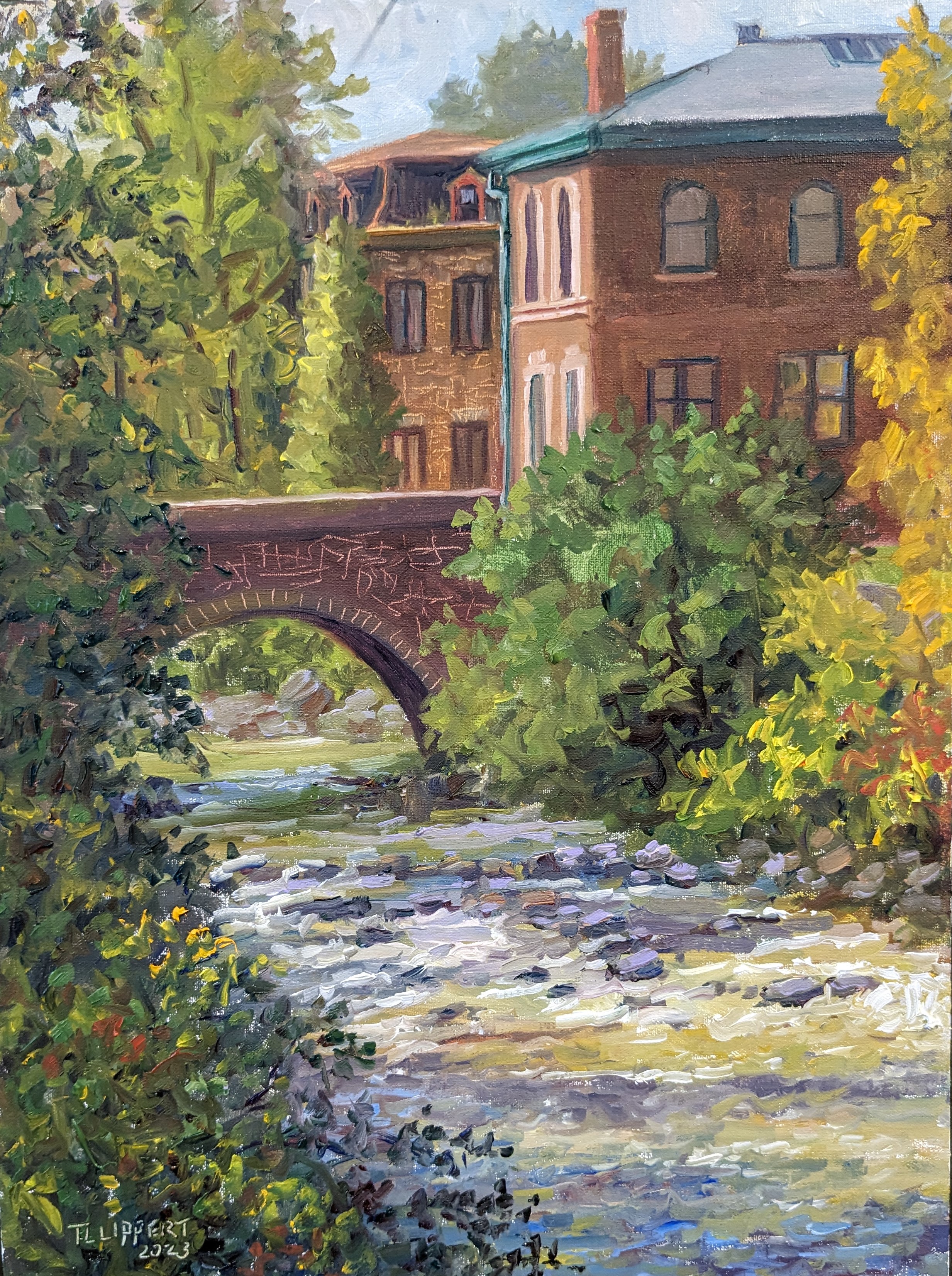 A plein air painting  by Tricia Lowry Lippert of trees and a bridge connecting to the brick buildings of the Silk complex next to the Karl Stirner Arts Trail in Easton, Pennsylvania