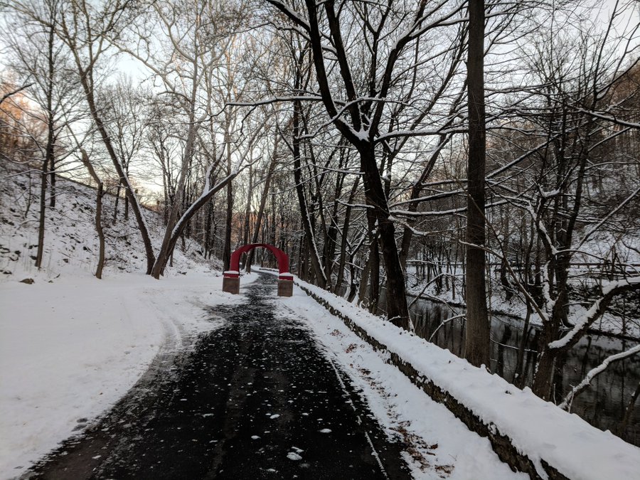 Snow covers each side of on the Karl Stirner Arts Trail with the red arch sculpture in the distance