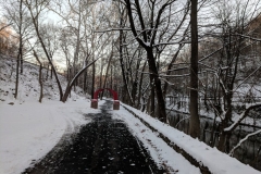 Snow covers each side of on the Karl Stirner Arts Trail with the red arch sculpture in the distance
