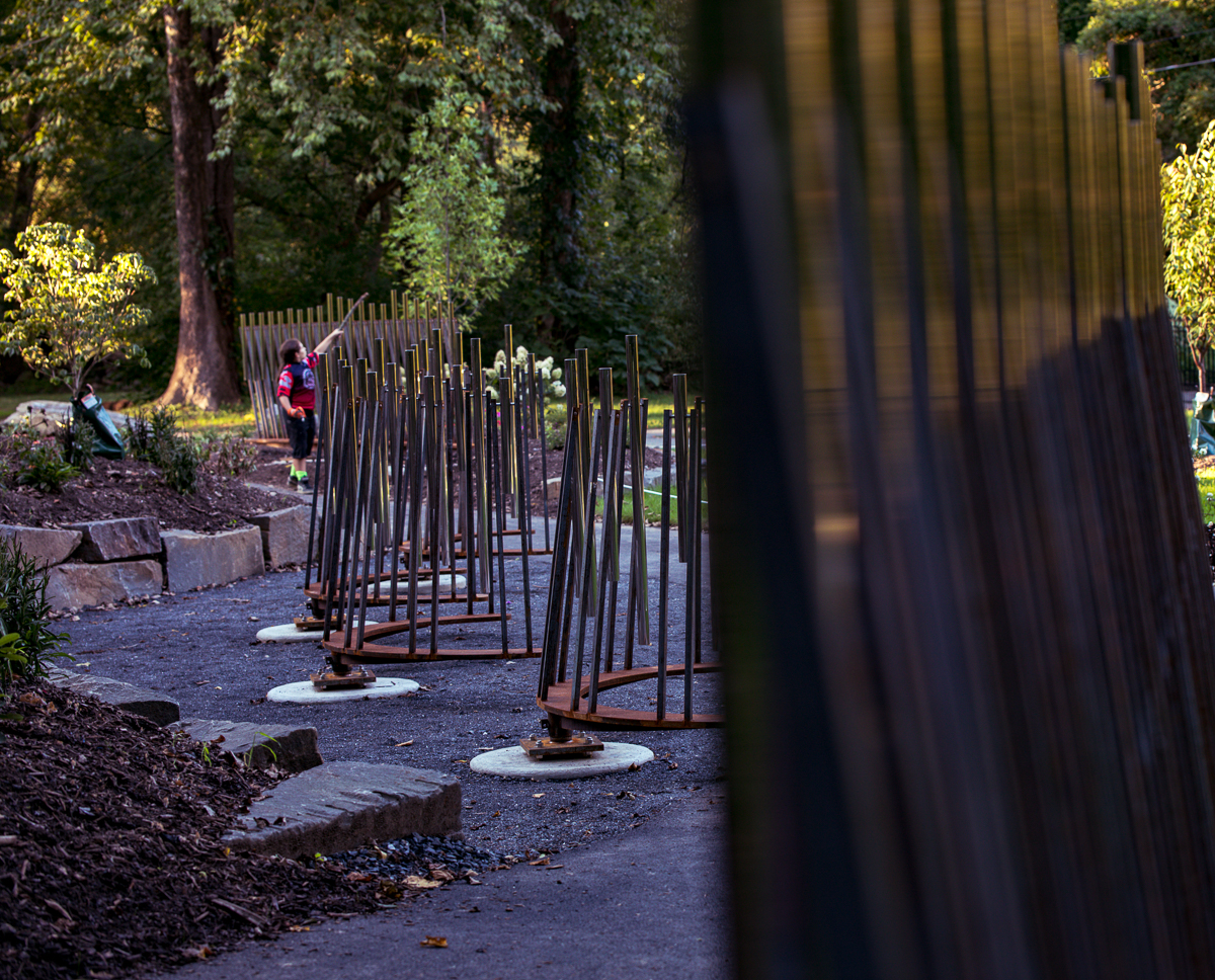A child uses a stick to play one of the Musical Path sets of musical rods on the Karl Stirner Arts Trail in Easton, Pennsylvania.
