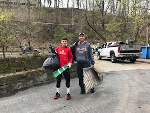 A man and his son carry trash during a cleanup day on the Karl Stirner Arts Trail in Easton, Pennsylvania.