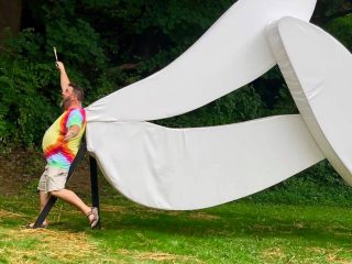 Danny Moyer stands by the white artwork resembling bugs' wings, called Love Motel for Insects, on the Karl Stirner Arts Trail in Easton, Pennsylvania.
