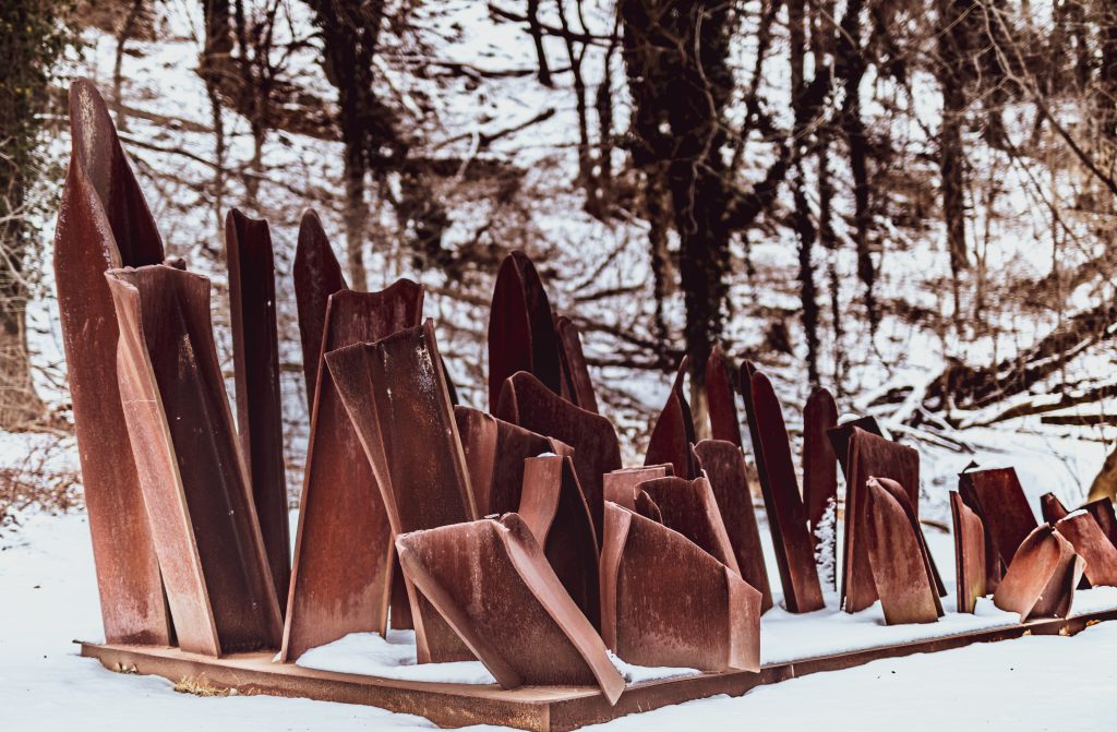 Sprouts, a metal sculpture by Steve Tobin consisting of many different partly bent scrap metal pieces, stands on the Karl Stirner Arts Trail with snow surrounding it in Easton, Pennsylvania.