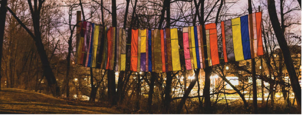 A banner of differnet colors hangs between trees on the Karl Stirner Arts Trail in Easton, Pennsylvania.