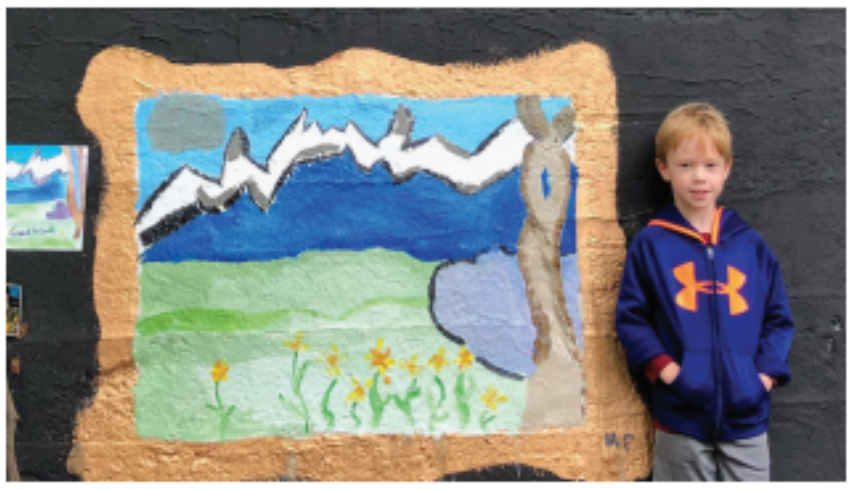 A boy stands by his painting of flowers and water on the Young Masters Wall on the Karl Stirner Arts Trail in Easton, Pennsylvania.
