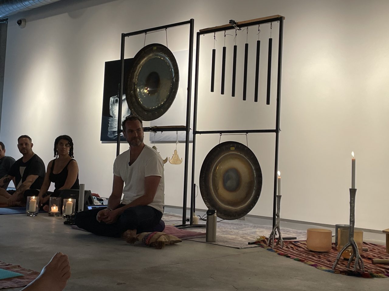 People sit on the floor by several hanging percussion instruments as part of the Sound Bath Experiences installation on the Karl Stirner Arts Trail in Easton, Pennsylvania