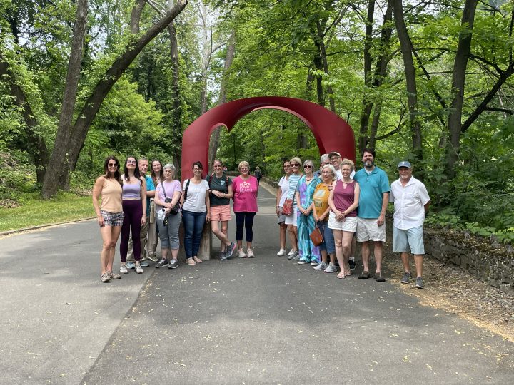 A group on the Walk and Talk led by Jim Toia pose for a photo at the red arch sculpture on the Karl Stirner Arts Trail in Easton, Pennsylvania.
