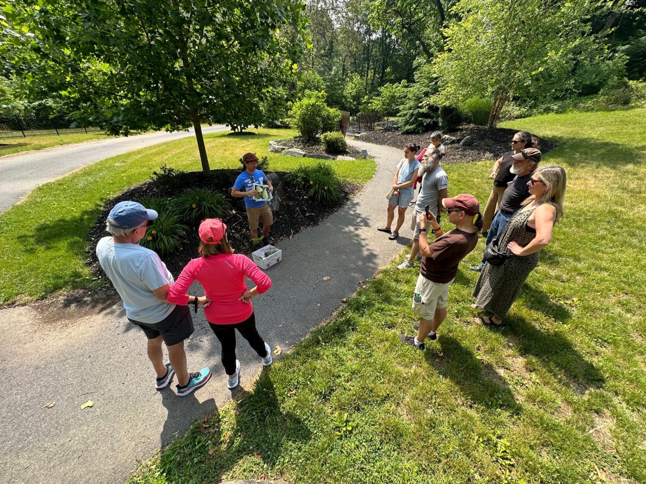 A group of nine people listen to Philip Chung discuss paw paw fruit during a recent event on the Karl Stirner Arts Trail in Easton, Pennsylvania.