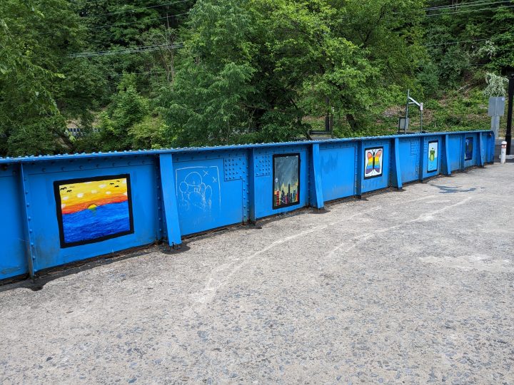 One side of the Richard McAteer Memorial Bridge with temporary paintings on the blue wall on the Karl Stirner Arts Trail in Easton, Pennsylvania