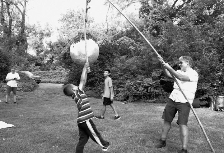 A boy with a stick takes a swing at a piñata held by Nestor Gil during the LaJiraGira community picnic on the Karl Stirner Arts Trail in Easton, Pennsylvania.