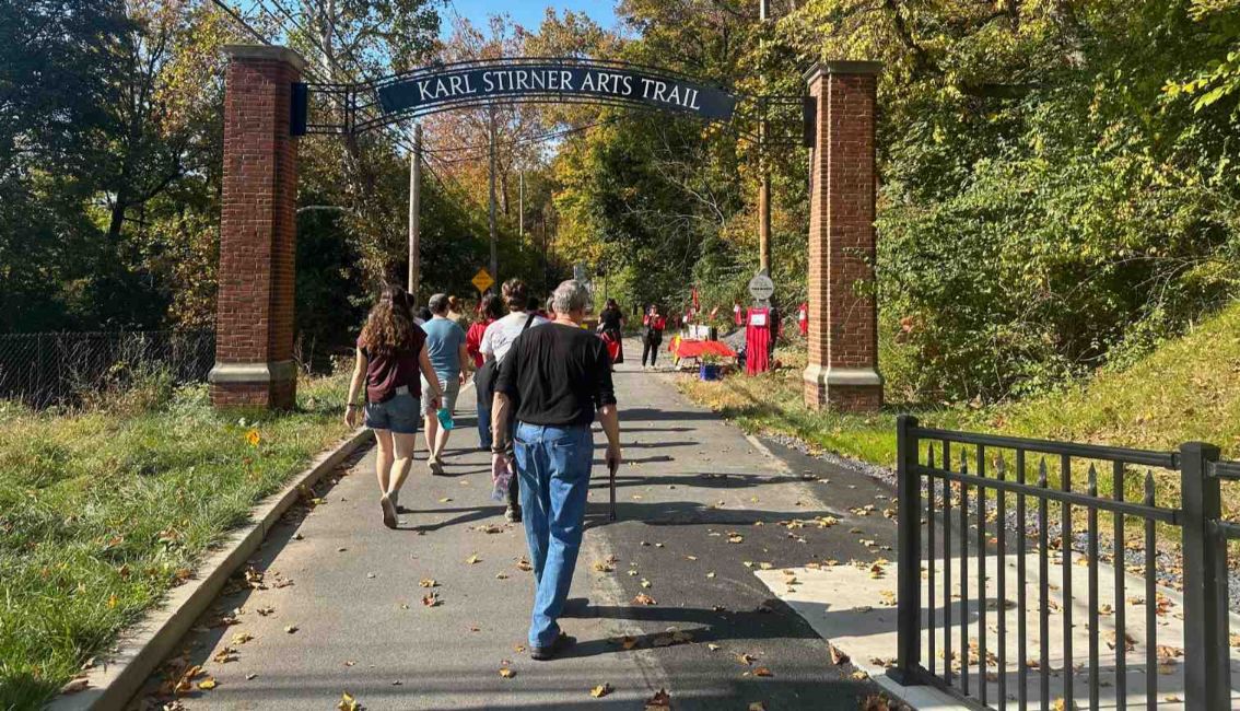 People walk to the Karl Stirner Arts Trail sign during the Walk for the Missing and Stolen event as part of the Red Sand Project on the Karl Stirner Arts Trail in Easton, Pennsylvania.