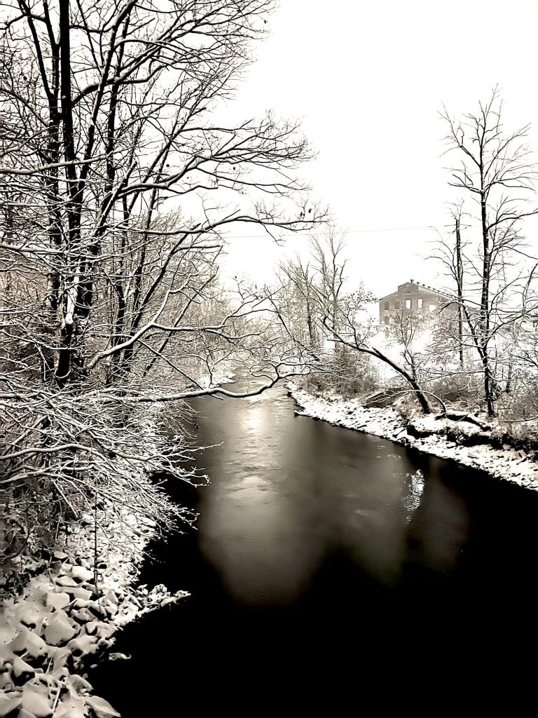The Bushkill Creek and trees on both sides covered by snow on the Karl Stirner Arts Trail in Easton, Pennsylvania