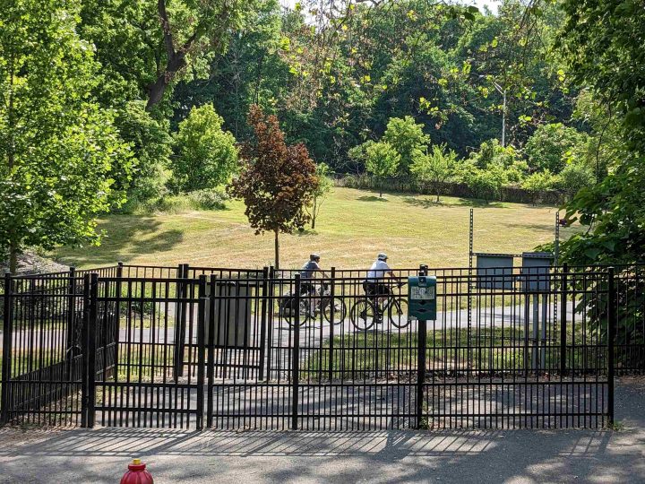 A view inside the dog park of two people riding their bicycles on the Karl Stirner Arts Trail in Easton, Pennsylvania