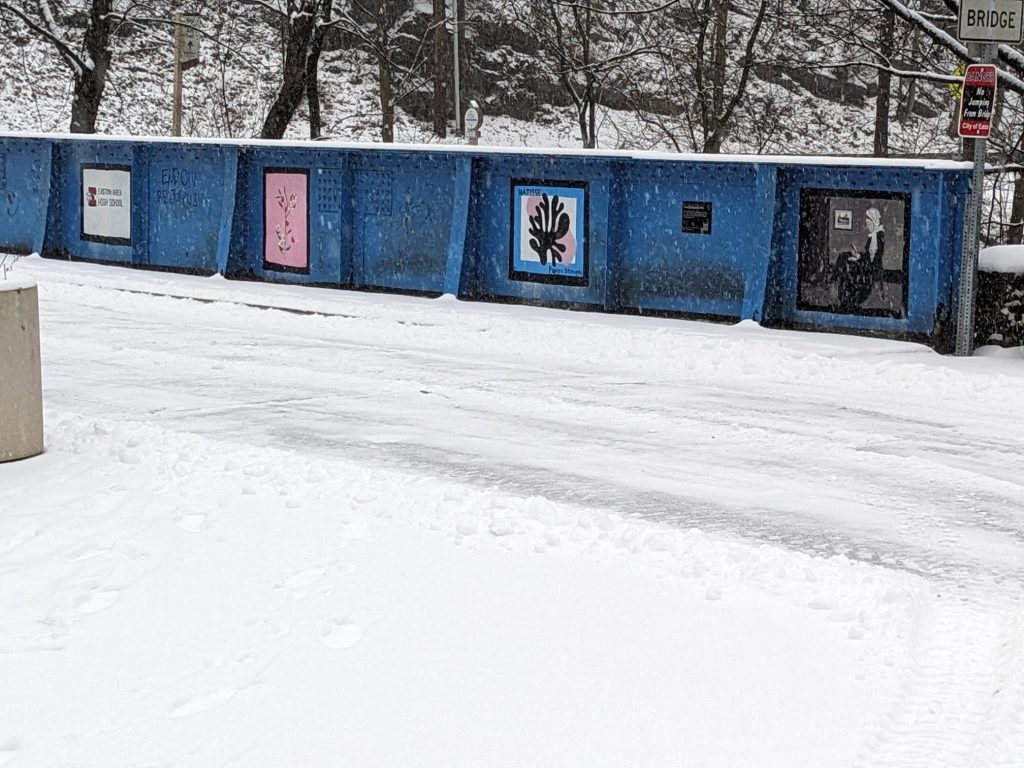 A portion of the blue Young Masters Wall during snowfall on the Karl Stirner Arts Trail in Easton, Pennsylvania