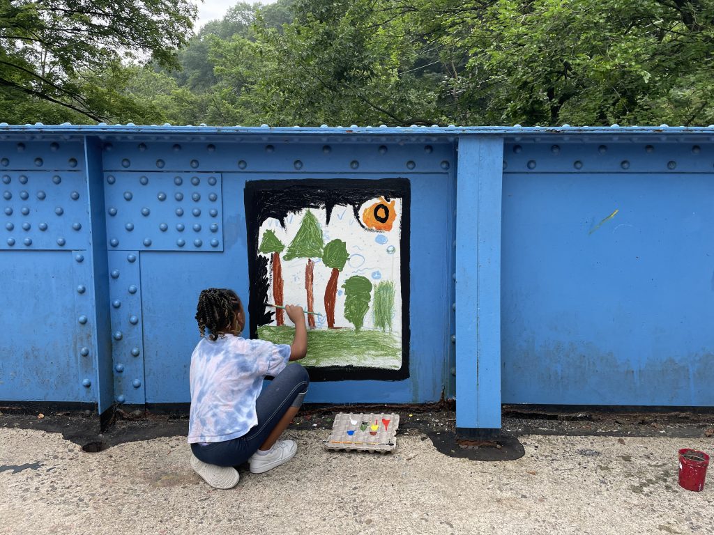 Young girl Lily Dineen paints a scene of trees on the Young Masters Wall on the Karl Stirner Arts Trail in Easton, Pennsylvania.