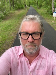 A selfie photo of Edward Shaughnessy with the pavement of the Karl Stirner Arts Trail behind him