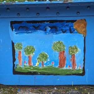 A painting of trees on grass with a blue sky and blue birds flying above adorns the Young Masters Wall at the Karl Stirner Arts Trail in Easton, Pennsylvania.