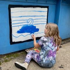 A girl paints a blue picture on Young Masters Wall at the Karl Stirner Arts Trail in Easton, Pennsylvania.