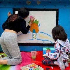 Two girls paint a pineapple together on the Young Masters Wall at the Karl Stirner Arts Trail in Easton, Pennsylvania.