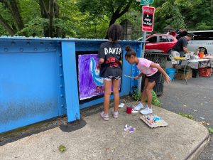 Two girls paint Stitch from the Disney movie Lilo and Stich on the Young Masters Wall at the Karl Stirner Arts Trail in Easton, Pennsylvania.