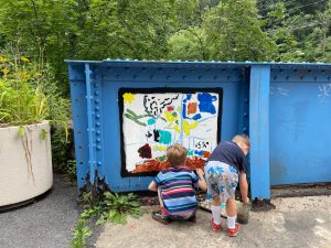 Two boys paint a picture together on the blue Young Masters Wall at the Karl Stirner Arts Trail in Easton, Pennsylvania.