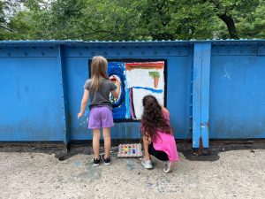 Two young girls paint a picture together on the Young Masters Wall at the Karl Stirner Arts Trail in Easton, Pennsylvania.