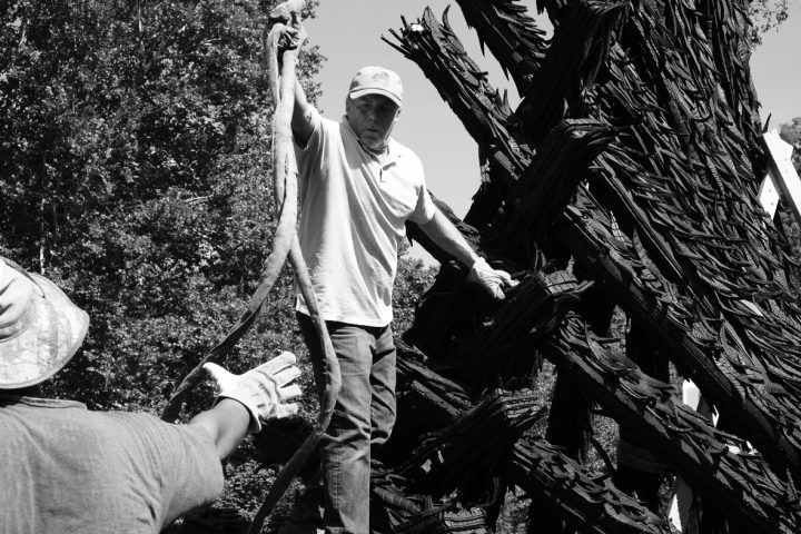 Jim Toia and another man work together to install the recycled rubber tire sculpture by Chakaia Booker, No More Milk and Cookies, on the Karl Stirner Arts Trail in Easton, Pennsylvania.