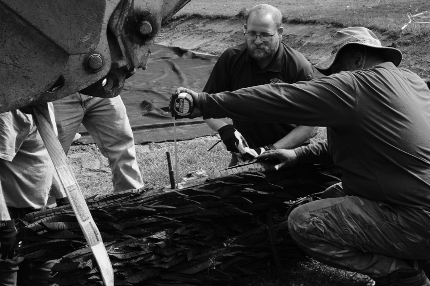 Three men work together to help install the recycled rubber tire sculpture by Chakaia Booker, No More Milk and Cookies, on the Karl Stirner Arts Trail in Easton, Pennsylvania.