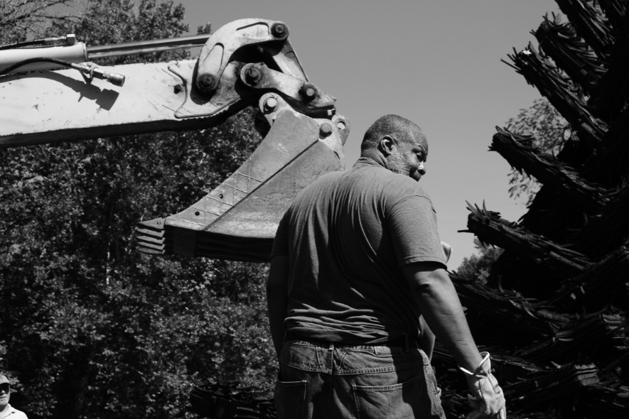 A man stands in front of construction machinery during the installation of the recycled rubber tire sculpture by Chakaia Booker, No More Milk and Cookies, on the Karl Stirner Arts Trail in Easton, Pennsylvania.