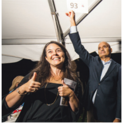 Melissa Starace raises her two thumbs and smiles as someone holds up a piece of paper with the number 93 in the background during a benefit event for the Karl Stirner Arts Trail in Easton, Pennsylvania.